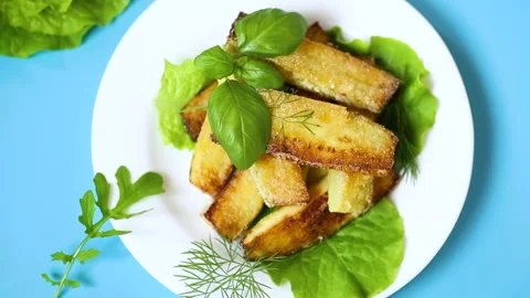 Zucchini with a crispy crust and fresh salad on a blue background Stock Footage 314418585