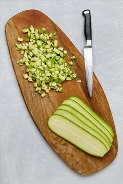 Zucchini cut into cubes and layers on a wooden cutting board on a concrete li Stock Photos