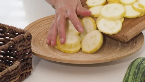 Zucchini slices close up on wooden plate on white background. Video stock 135679341