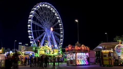 Zurich fun fair with fast Ferris wheel, strolling passers-by, time-lapse Stock Footage