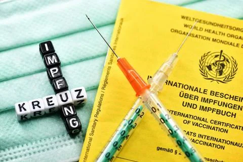 Zwei gekreuzte Spritzen mit Impfpass und Schriftzug Kreuzimpfung *** Two c... Stock Photos